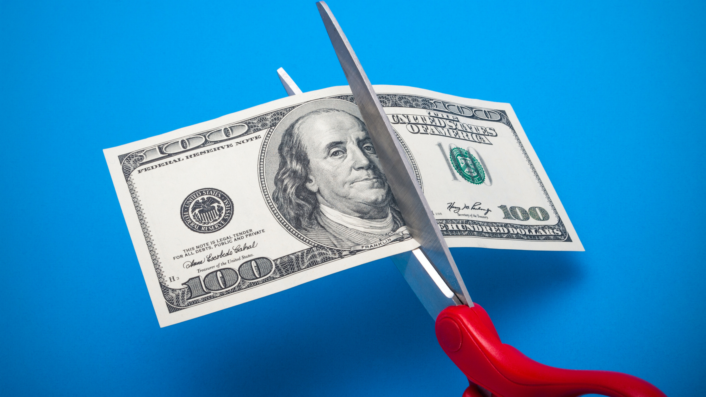 scissor cutting a $100 bill