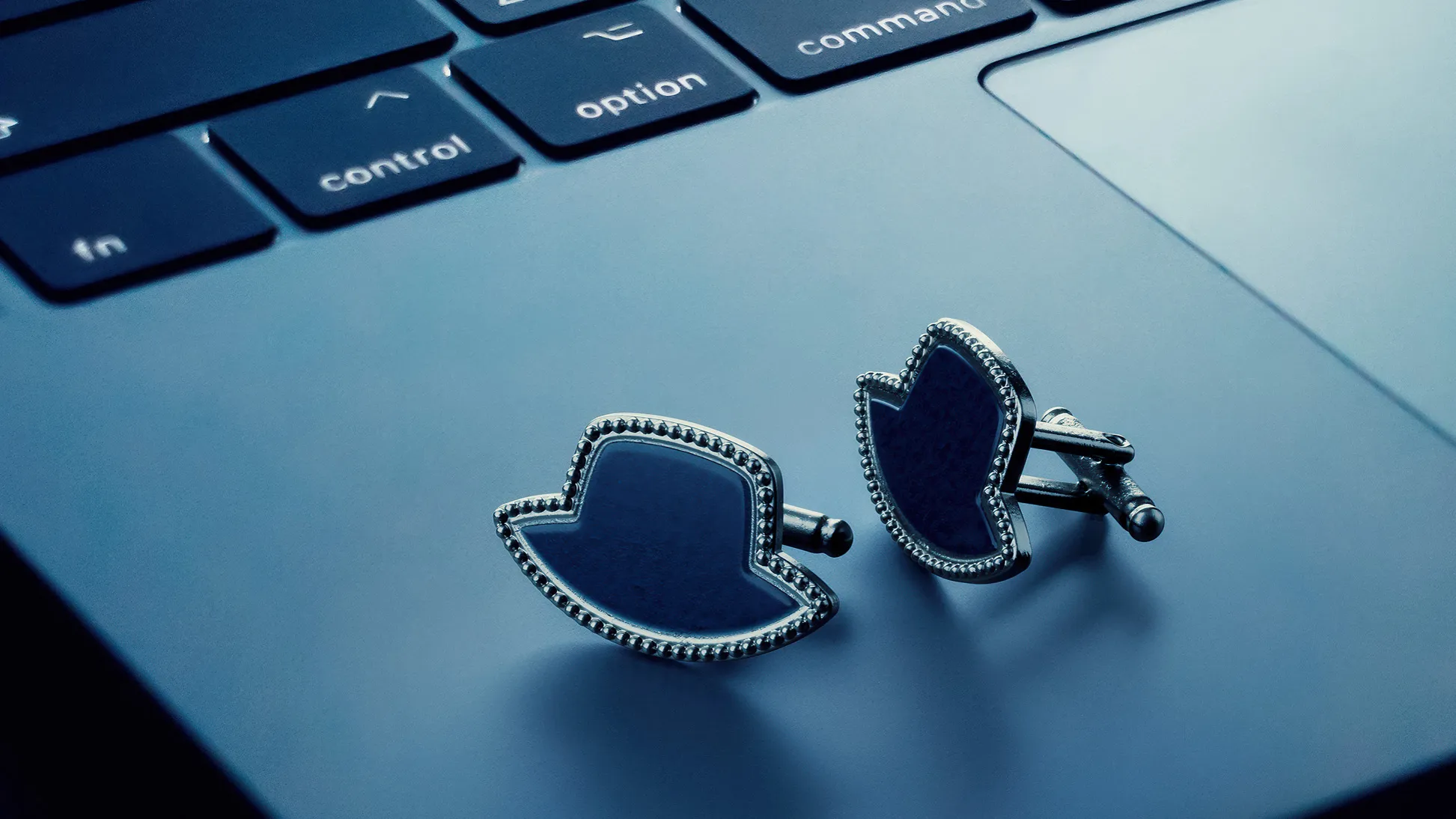 diamond black hat-shaped cuff links on a laptop computer